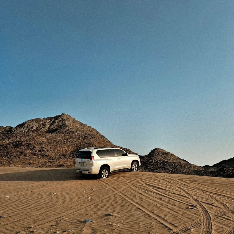 SUV in the desert beside dramatic rocky mountains